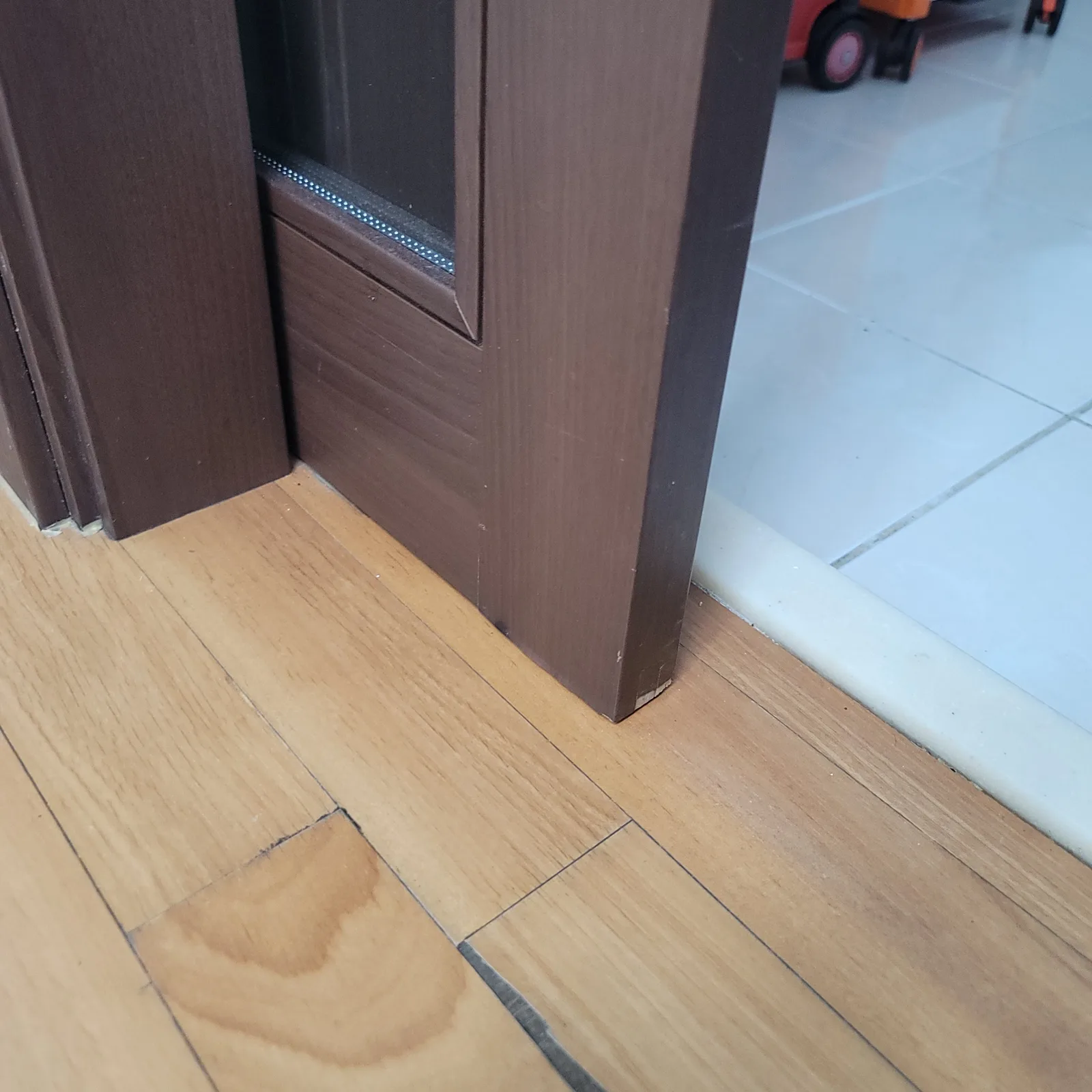 문틀 하단 모서리가 마루 바닥과 만나는 지점을 가까이서 찍은 사진이다.